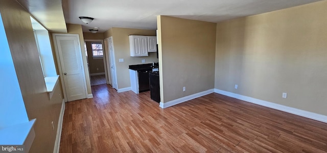 kitchen with white cabinets, baseboards, and wood finished floors