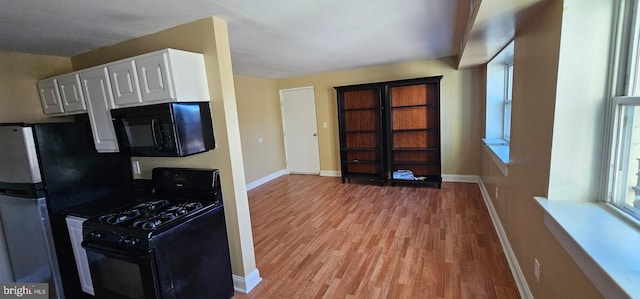 kitchen featuring baseboards, white cabinetry, light wood finished floors, and black appliances