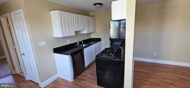 kitchen featuring black gas range, white cabinets, dishwasher, wood finished floors, and a sink