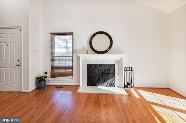 unfurnished living room featuring visible vents, wood finished floors, a high end fireplace, and baseboards