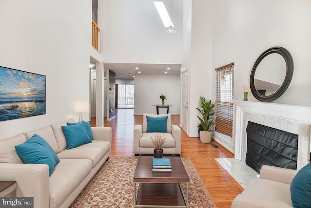 living room with a skylight, visible vents, wood finished floors, and a high end fireplace