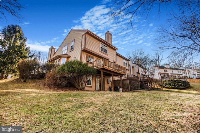 rear view of house featuring a chimney, a deck, and a lawn