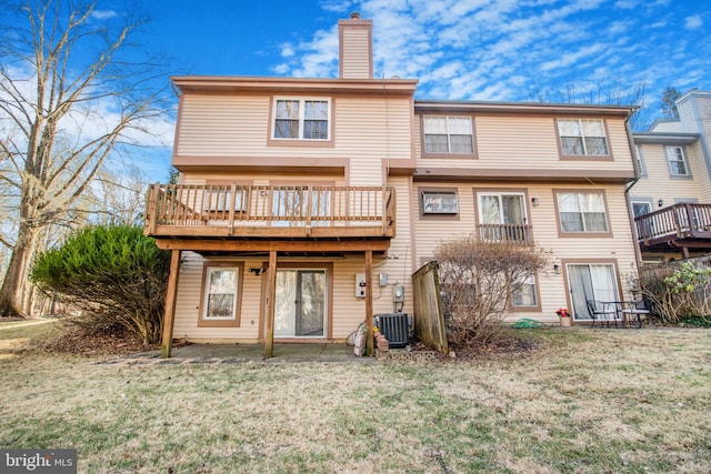 back of property with a chimney, a deck, and a lawn