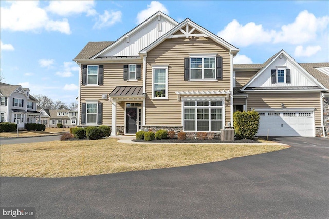 view of front of home featuring board and batten siding, a front yard, a standing seam roof, metal roof, and driveway