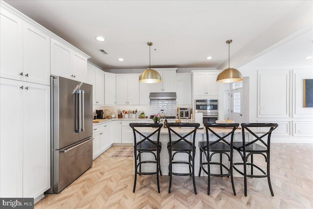 kitchen with visible vents, appliances with stainless steel finishes, under cabinet range hood, a kitchen bar, and white cabinetry