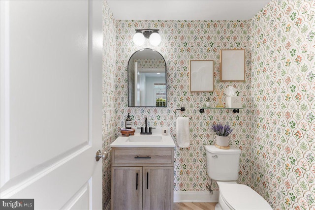 bathroom featuring vanity, toilet, and wallpapered walls