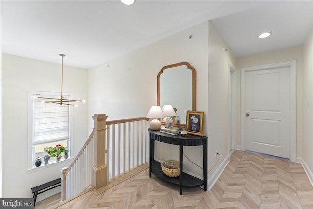 hallway featuring a chandelier, recessed lighting, baseboards, and an upstairs landing