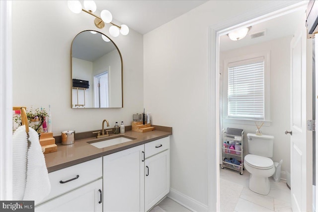 bathroom with baseboards, visible vents, vanity, and toilet