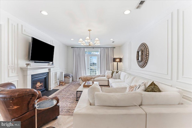 living room with a fireplace with flush hearth, recessed lighting, visible vents, and a decorative wall