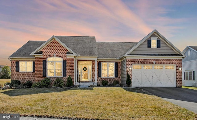 view of front of property with brick siding, a lawn, an attached garage, and aphalt driveway