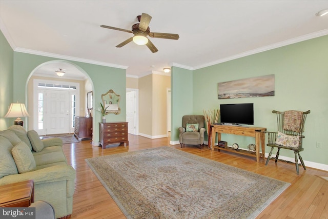 living room with arched walkways, crown molding, wood finished floors, and baseboards