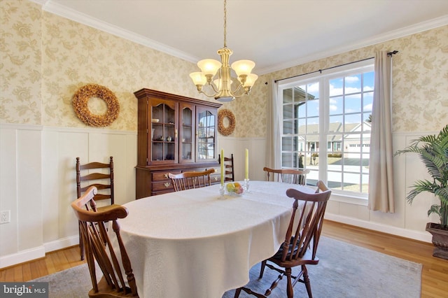 dining space featuring light wood-type flooring, wainscoting, and wallpapered walls