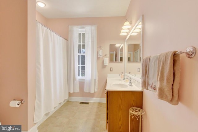 full bathroom with double vanity, baseboards, visible vents, a shower with curtain, and a sink