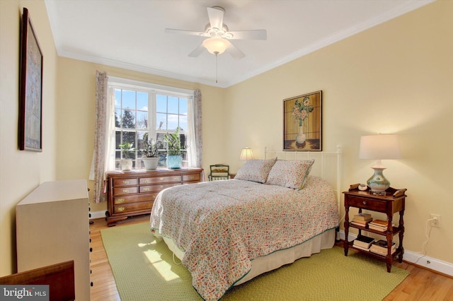 bedroom featuring baseboards, ceiling fan, light wood finished floors, and crown molding