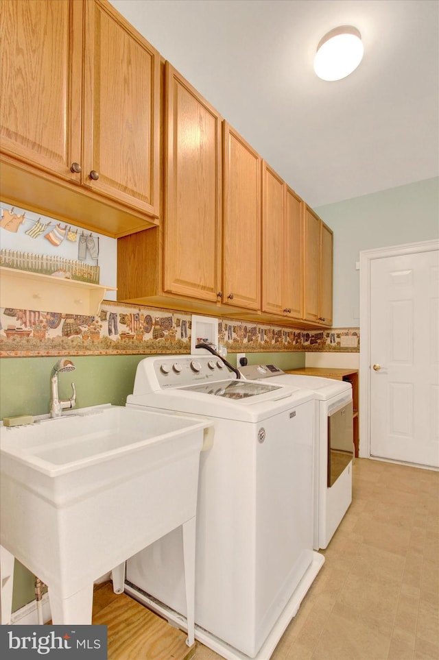 laundry room with cabinet space, a sink, and washing machine and clothes dryer