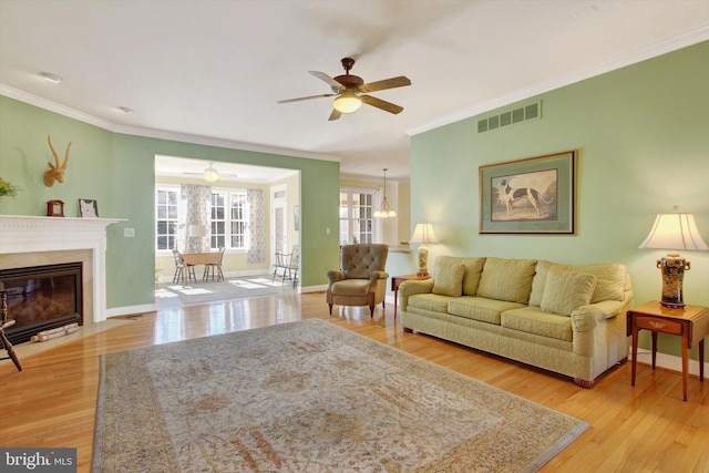 living room featuring light wood-style flooring, visible vents, and ornamental molding