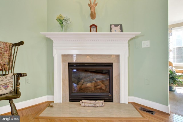 details featuring baseboards, a premium fireplace, visible vents, and wood finished floors