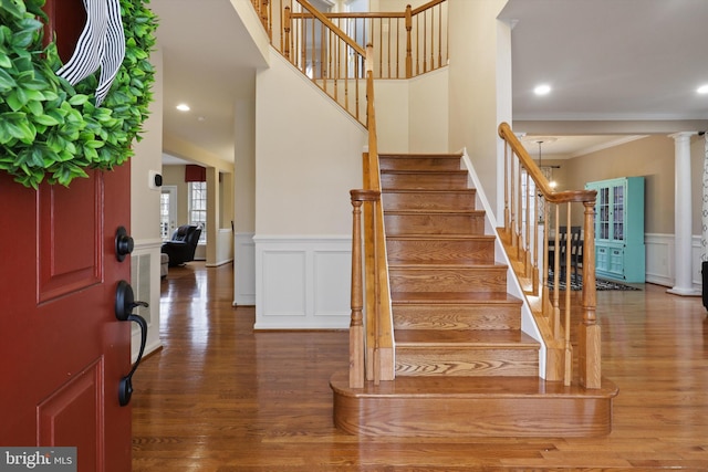 entrance foyer with wainscoting, wood finished floors, stairs, and ornamental molding