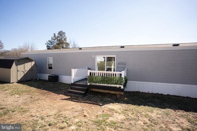 rear view of house with an outbuilding, central AC, a deck, and a storage shed