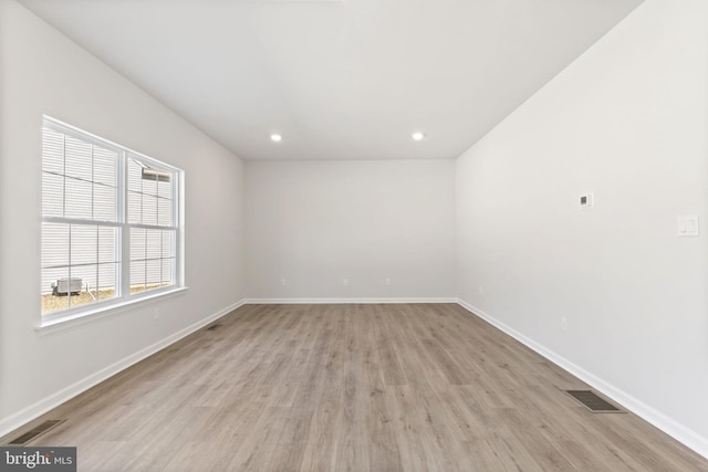 unfurnished room featuring light wood finished floors, visible vents, and baseboards