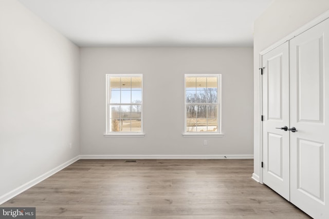 unfurnished bedroom featuring a closet, wood finished floors, and baseboards