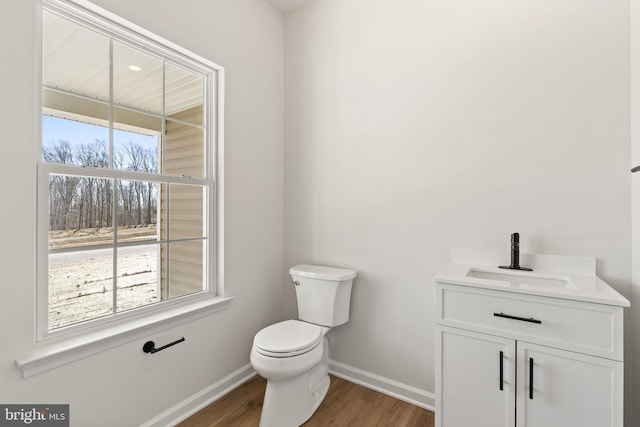 bathroom featuring baseboards, a sink, toilet, and wood finished floors