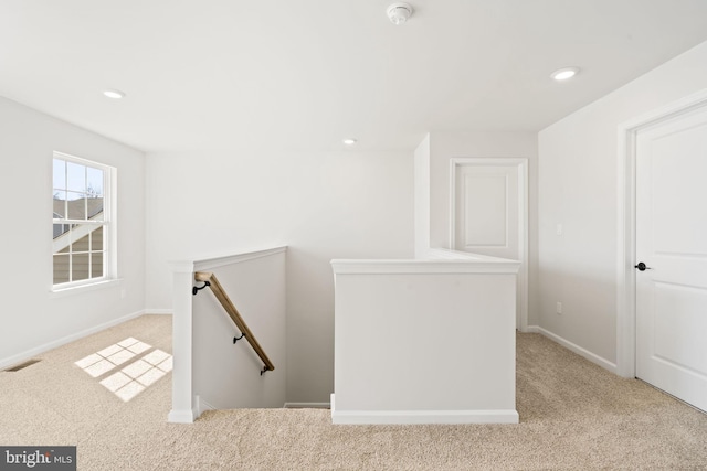 corridor featuring carpet floors, recessed lighting, visible vents, and an upstairs landing