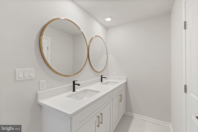 bathroom with double vanity, a sink, and baseboards