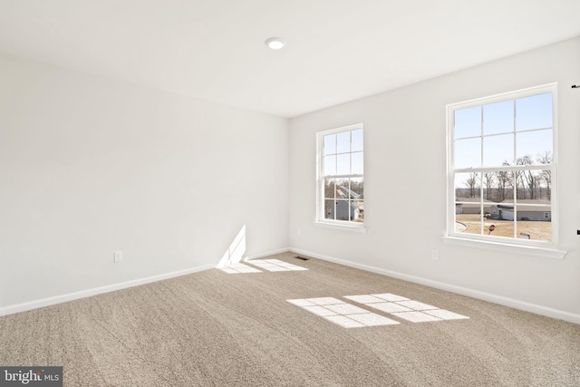 carpeted spare room with visible vents and baseboards