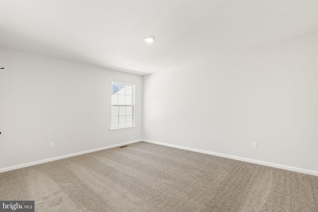 empty room featuring carpet floors, visible vents, and baseboards