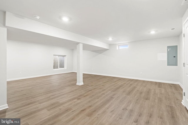 below grade area with light wood-style flooring, electric panel, baseboards, and recessed lighting