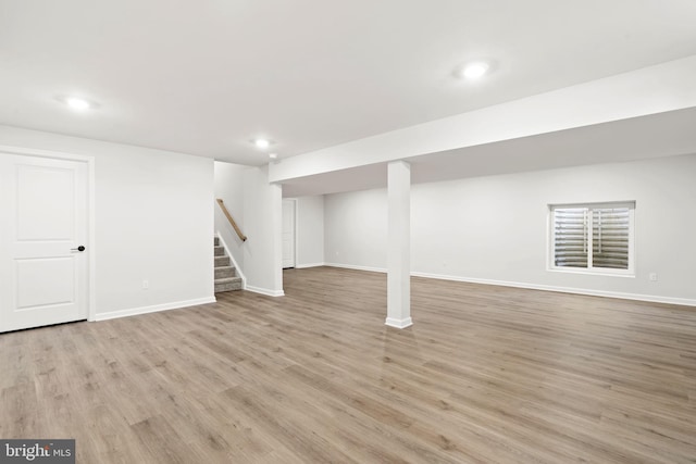 finished below grade area featuring light wood-style floors, stairs, baseboards, and recessed lighting