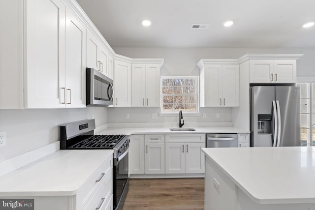 kitchen featuring visible vents, white cabinets, stainless steel appliances, a sink, and recessed lighting