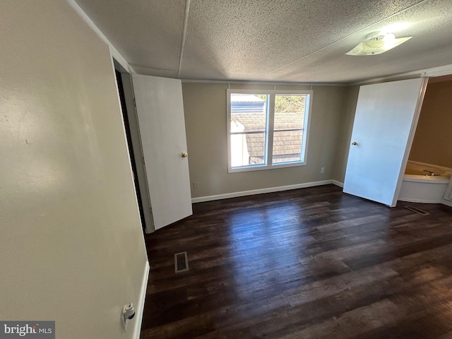 unfurnished bedroom featuring dark wood-style floors, visible vents, a textured ceiling, and baseboards