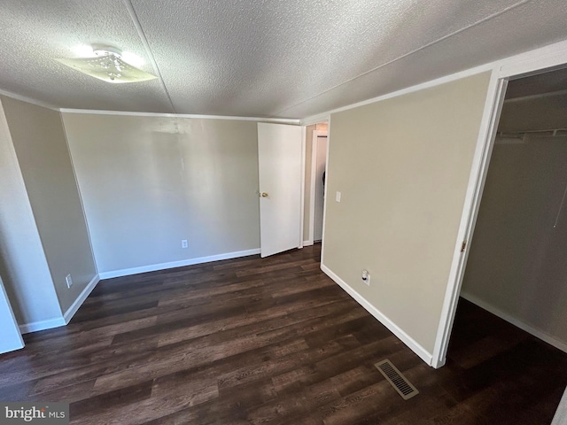 unfurnished bedroom featuring a textured ceiling, dark wood finished floors, visible vents, and baseboards