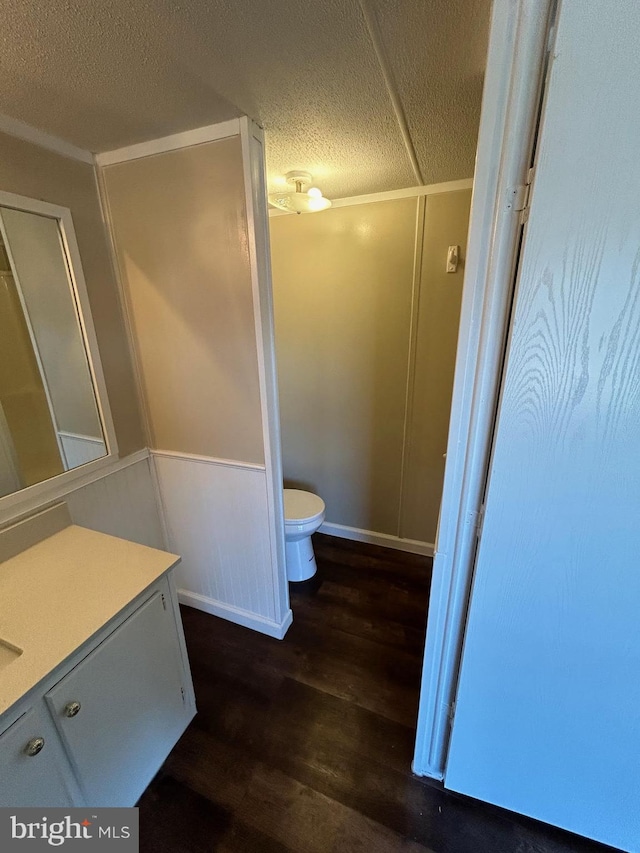 bathroom with a textured ceiling, toilet, wood finished floors, and vanity