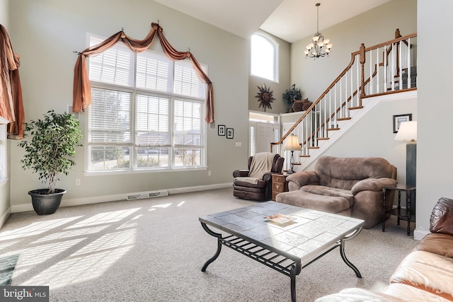 carpeted living room with a notable chandelier, visible vents, a high ceiling, baseboards, and stairs