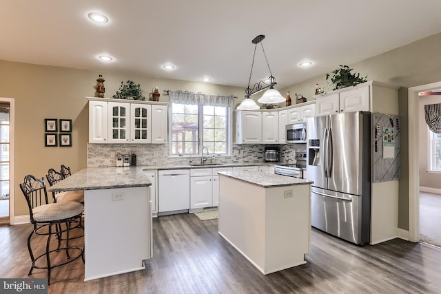 kitchen featuring a peninsula, a sink, a kitchen breakfast bar, white cabinets, and appliances with stainless steel finishes