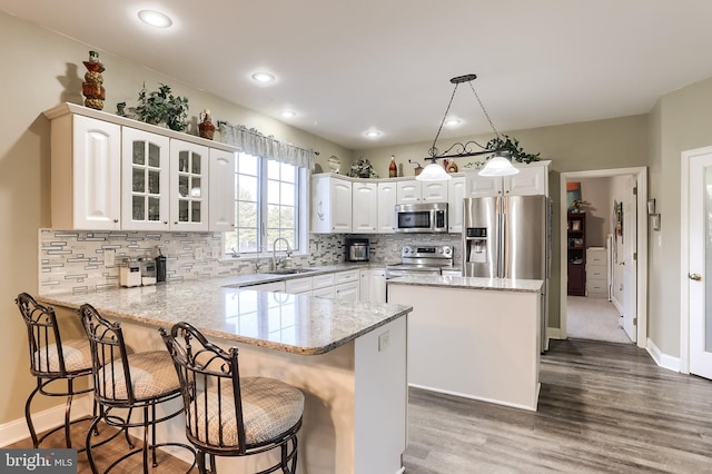 kitchen featuring a peninsula, appliances with stainless steel finishes, a sink, and white cabinetry