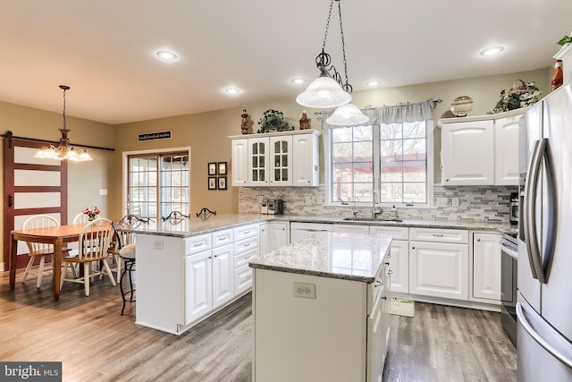 kitchen with light wood-style floors, white cabinets, a sink, and a peninsula