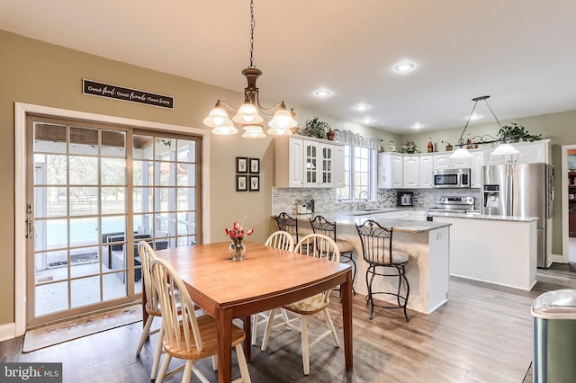 dining space featuring recessed lighting, light wood-type flooring, and an inviting chandelier