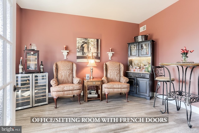 sitting room featuring wine cooler, visible vents, and wood finished floors