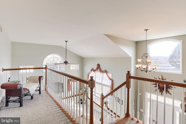 hallway with carpet floors, lofted ceiling, an upstairs landing, and an inviting chandelier