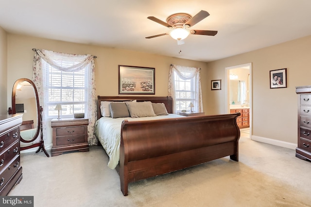 bedroom featuring light carpet, baseboards, a ceiling fan, and ensuite bathroom