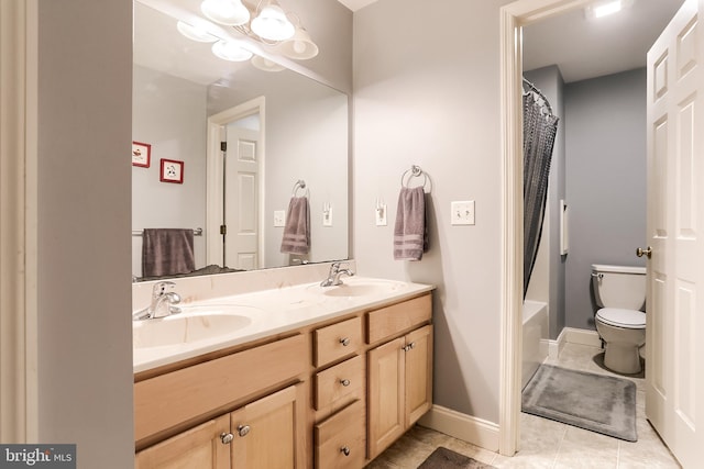 full bath featuring double vanity, toilet, a sink, and tile patterned floors