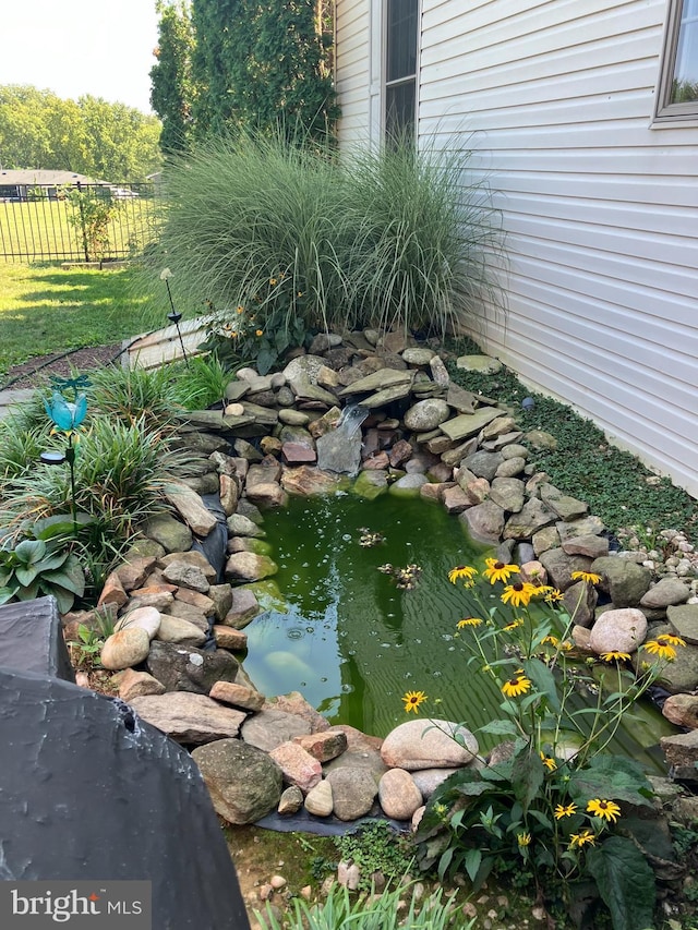 view of yard featuring fence and a small pond