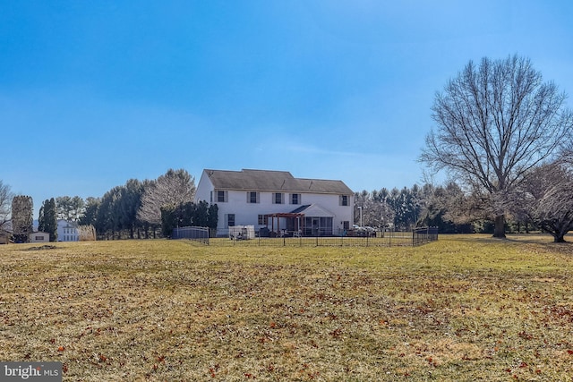 rear view of property featuring a lawn and fence