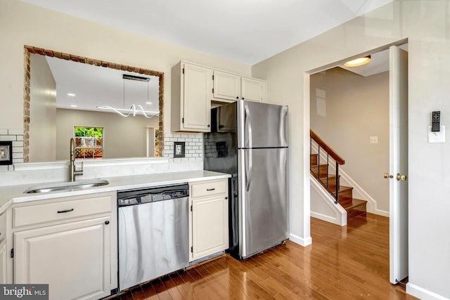 kitchen featuring wood finished floors, a sink, white cabinetry, appliances with stainless steel finishes, and backsplash