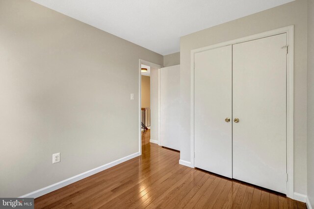 unfurnished bedroom with light wood-style floors, a closet, and baseboards