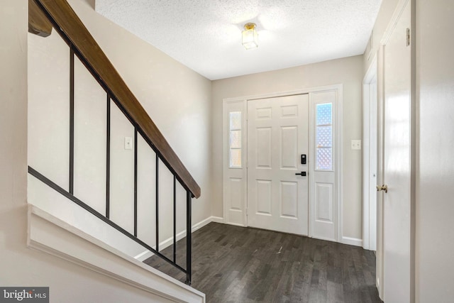 foyer entrance with dark wood-style floors, a textured ceiling, baseboards, and stairs